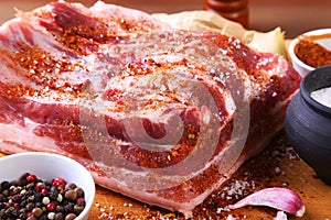 Raw fresh meat, uncooked lamb or beef ribs with pepper, garlic, salt and spices on dark stone background, Ready for