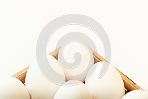 Raw fresh organic eggs in wicker plate on white background. Ingredient of healthy eating