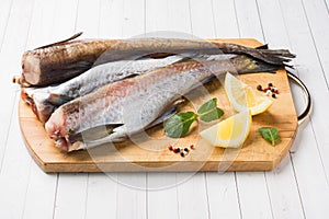 Raw fresh Pollock fish on a wooden Board with lemon