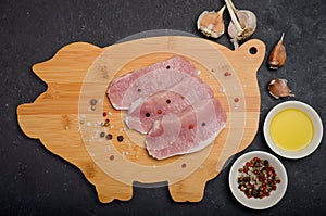 Raw fresh pork meat on wooden board on black background
