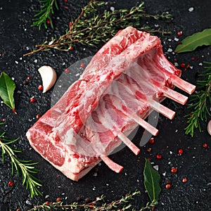 Raw fresh rack of lamb with green herbs.