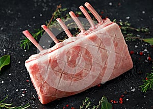 Raw fresh rack of lamb with green herbs.