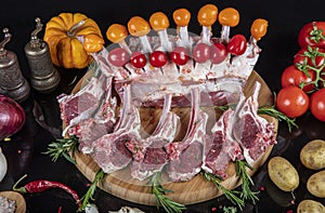 Raw fresh rack of lamb with green herbs. Racks of lamb ready for cooking on dark background. Raw ribs with a rosemary and