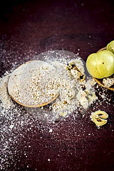 Raw fresh ripe Phyllanthus emblica,amla or Indian gooseberry with its powder on wooden surface.