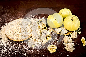 Raw fresh ripe Phyllanthus emblica,amla or Indian gooseberry with its powder on wooden surface.