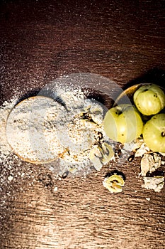 Raw fresh ripe Phyllanthus emblica,amla or Indian gooseberry with its powder on wooden surface.
