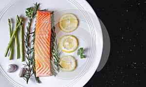 Raw fresh salmon fillet with herbs and ingredients, on white dish