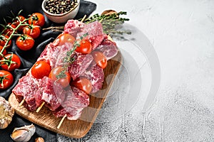 Raw fresh shish kebab. BBQ meat with tomato and spices. Gray background. Top view. Copy space