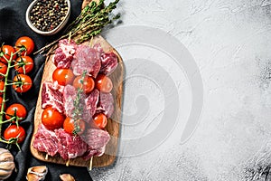 Raw fresh shish kebab. BBQ meat with tomato and spices. Gray background. Top view. Copy space