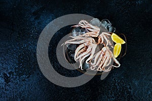 Raw fresh squid tentacles on a black concrete background, top view, text space