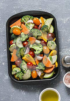 Raw fresh vegetables on a baking sheet. Sweet potato, zucchini, sweet pepper, cherry tomatoes, garlic, broccoli cabbage, olive oil