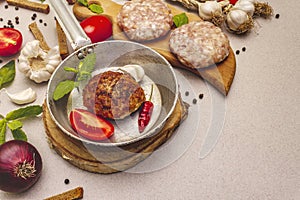 Raw and fried cutlets, fresh vegetables, spices, olive oil. Vintage pan, picnic or barbecue cooking concept