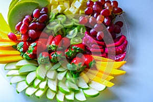 Raw fruits assortment platter on the white plate, on the white table.