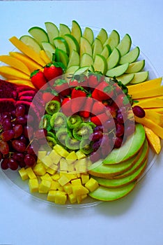 Raw fruits assortment platter on the white plate, on the white table.