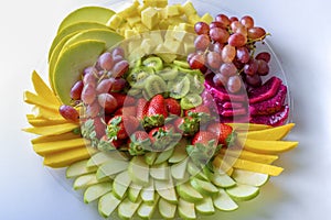 Raw fruits assortment platter on the white plate, on the white table.Top view.