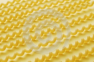 Raw fusilli lunghi pasta over yellow background