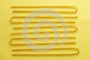 Raw fusilli lunghi pasta over yellow background