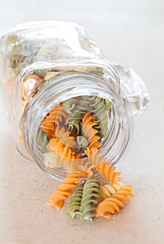 Raw fusilli pasta with glass bottle