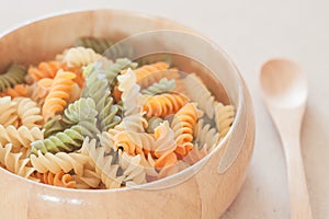 Raw fusilli pasta on wooden bowl