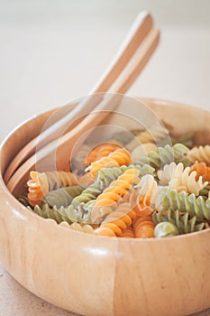 Raw fusilli pasta on wooden bowl