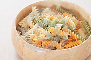 Raw fusilli pasta on wooden bowl