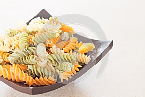 Raw fusilli pasta on wooden tray