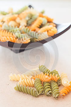 Raw fusilli pasta on wooden tray