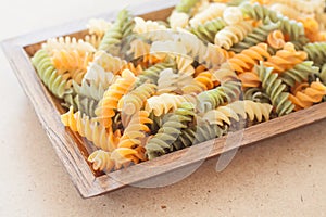 Raw fusilli pasta on wooden tray