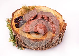Raw game meat, beef on chopping block, wood slice, isolated. Steaks, pieces of red meat, roe deer meat on wood. photo