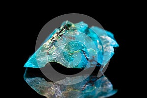 Raw gemstone in front of black, blue Chrysocolla mineral stone