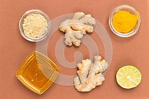 Raw ginger root and dry ginger on brown background. Honey in glass bowl