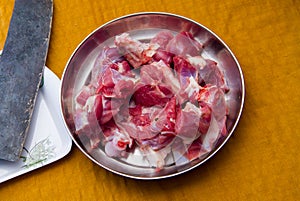 Raw goat red meat pieces with big knife  in a steel plate