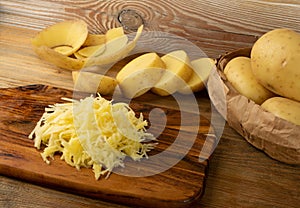 Raw Grated Potato on Wooden Cutting Board Background