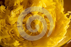 Raw grated potato on wooden cutting board in glass bowl closeup