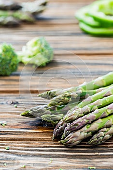 Raw green asparagus and veggies on wooden table. Selective focus