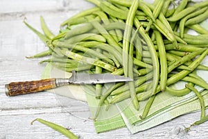 Raw green beans (Phaseolus vulgaris) antique knife on cloth napkin