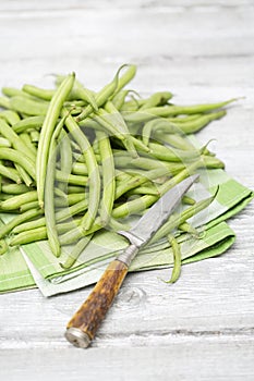 Raw green beans (Phaseolus vulgaris) antique knife on cloth napkin