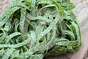 Raw green fettuccine nests on wooden board