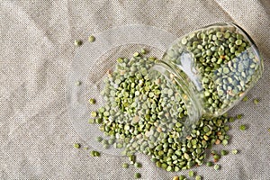 Raw green peas in glass jar over wooden background, close-up, selective focus.