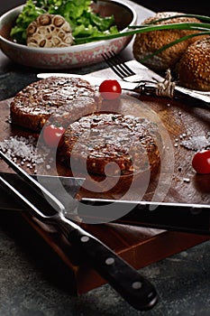 Raw Ground beef meat Burger steak cutlets with ingredients on the board.