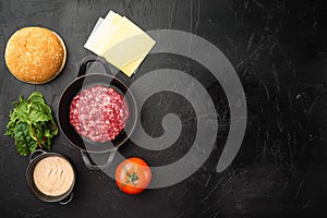 Raw Ground beef meat Burger steak cutlets with ingredients and buns, on black stone background, top view flat lay, with copy space