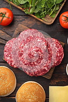 Raw Ground beef meat Burger steak cutlets with ingredients and buns, on old dark  wooden table background, top view flat lay