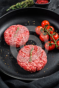 Raw Ground beef meat Burger steak cutlets in a pan. Black background. Top view