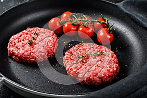 Raw Ground beef meat Burger steak cutlets in a pan. Black background. Top view