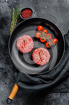 Raw Ground beef meat Burger steak cutlets in a pan. Black background. Top view