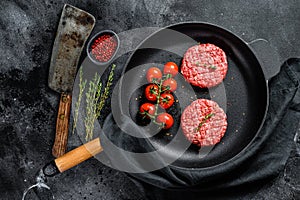 Raw Ground beef meat Burger steak cutlets in a pan. Black background. Top view