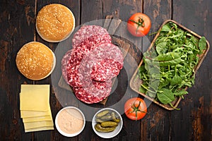 Raw Ground beef meat Burger steak cutlets and seasonings with buns, on old dark  wooden table background, top view flat lay