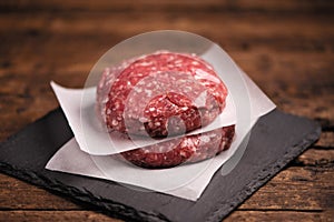 Raw ground beef meat burger steak cutlets on wooden background