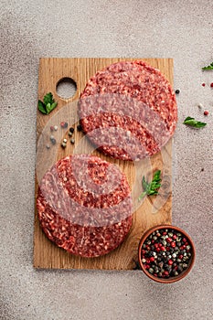 Raw Ground beef meat Burger steak cutlets on a wooden board, Food recipe background. Close up, vertical image. top view