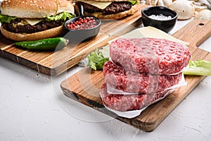 Raw ground beef meat cutlets for burger on white textured background